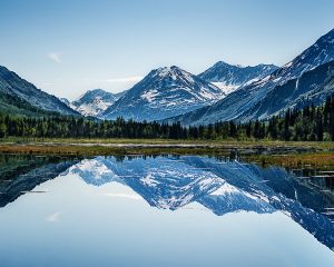 Windless day provided a smooth lake as a mirror for a snow capped mountain.